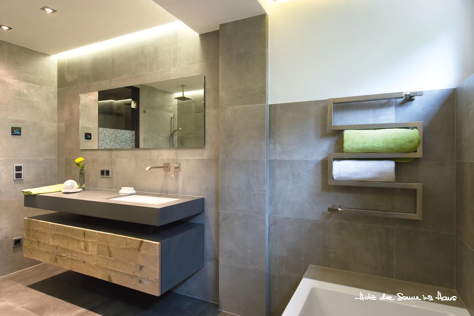 Bad mit grauen Fliesen, Holzdetail und runder Badewanne